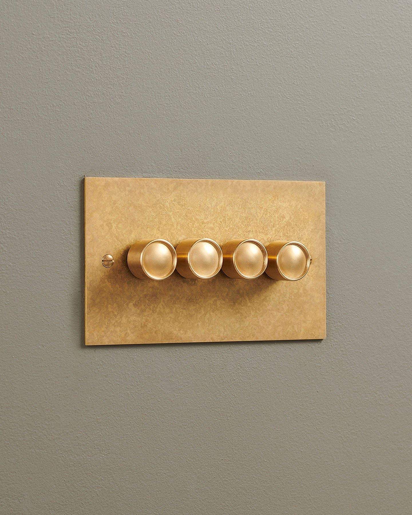 An oblique view of a 4 gang classic dimmer switch in a mottled aged brass finish.