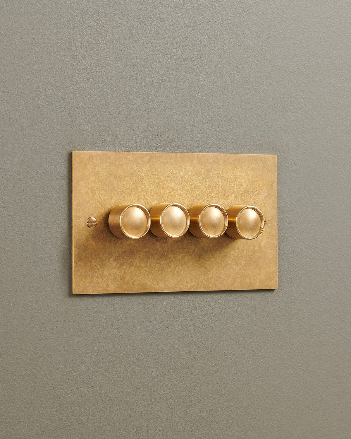 An oblique view of a 4 gang classic dimmer switch in a mottled aged brass finish. TEST