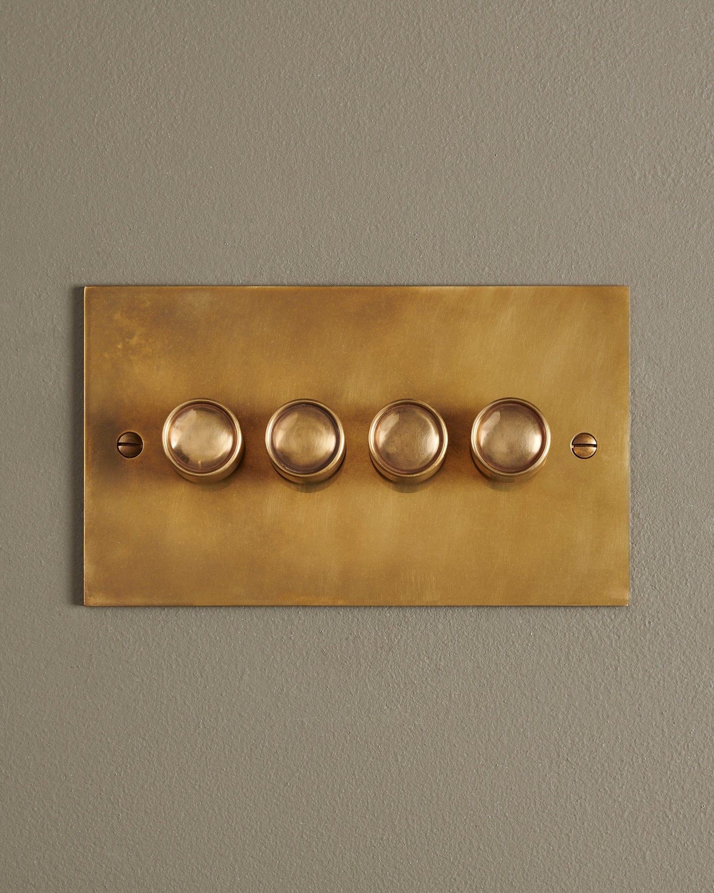 A straight-on view of a 4 gang classic dimmer switch in a warm burnished brass finish.