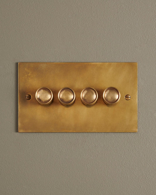 A straight-on view of a 4 gang classic dimmer switch in a warm burnished brass finish.