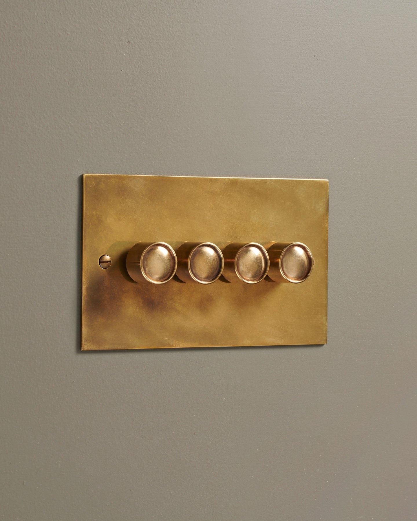 An oblique view of a 4 gang classic dimmer switch in a warm burnished brass finish.