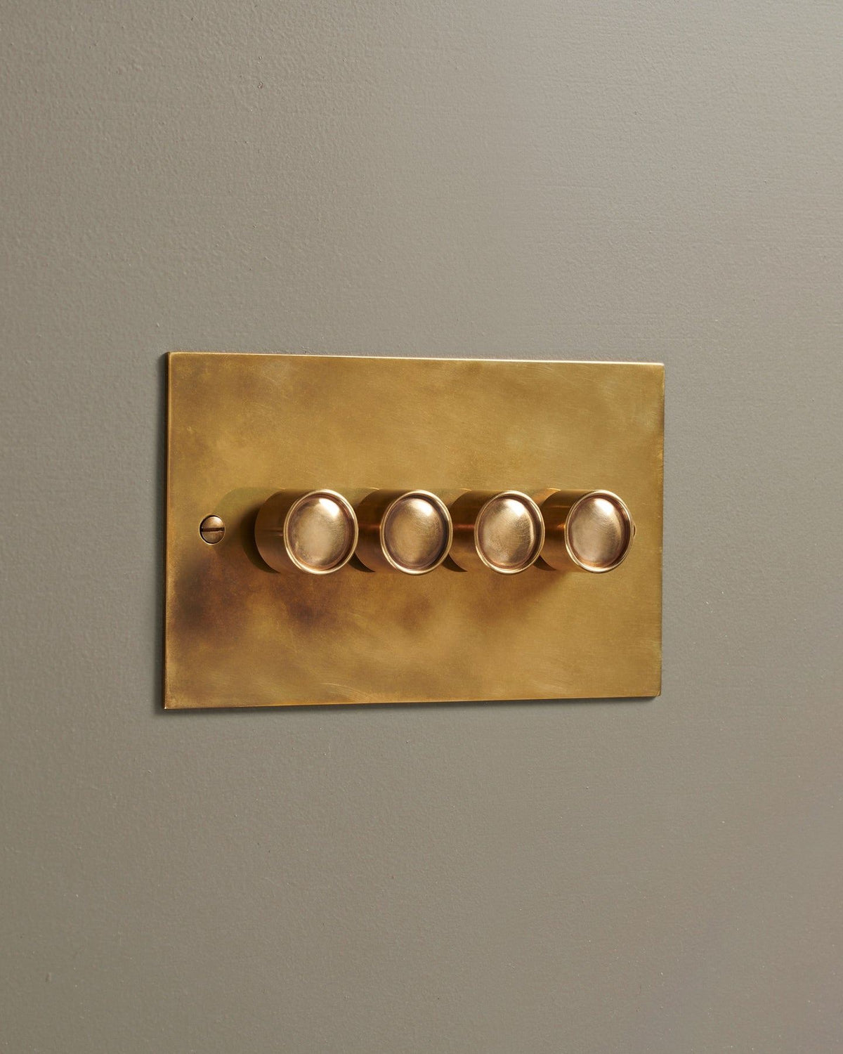 An oblique view of a 4 gang classic dimmer switch in a warm burnished brass finish. TEST