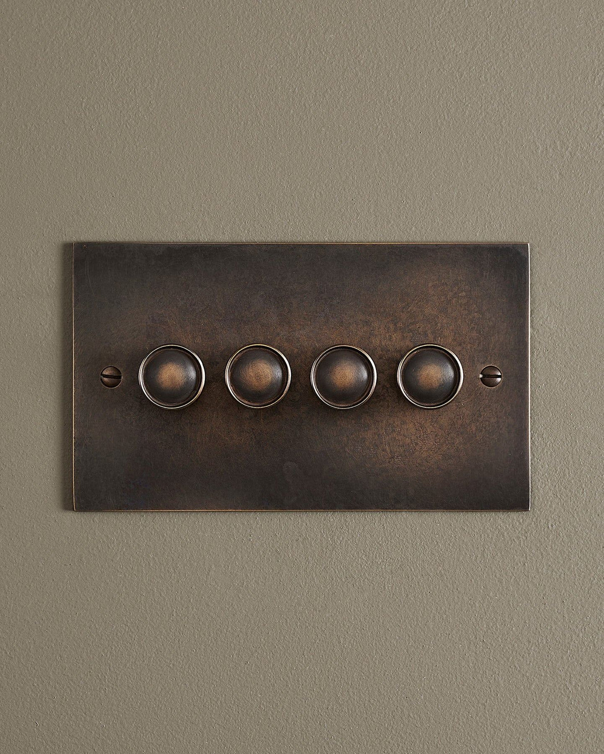 A straight-on view of a 4 gang classic dimmer switch in a dark oxidised brass finish. TEST