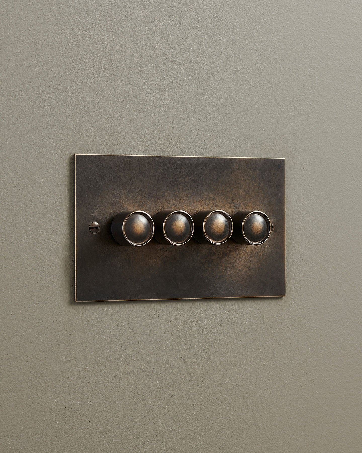 An oblique view of a 4 gang classic dimmer switch in a dark oxidised brass finish.