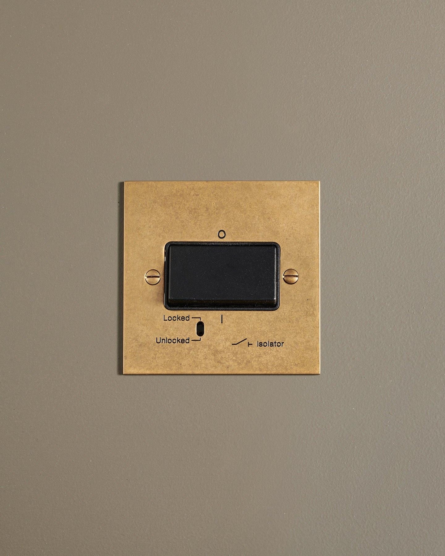 A straight-on view of a classic extractor fan isolator switch a mottled aged brass finish.
