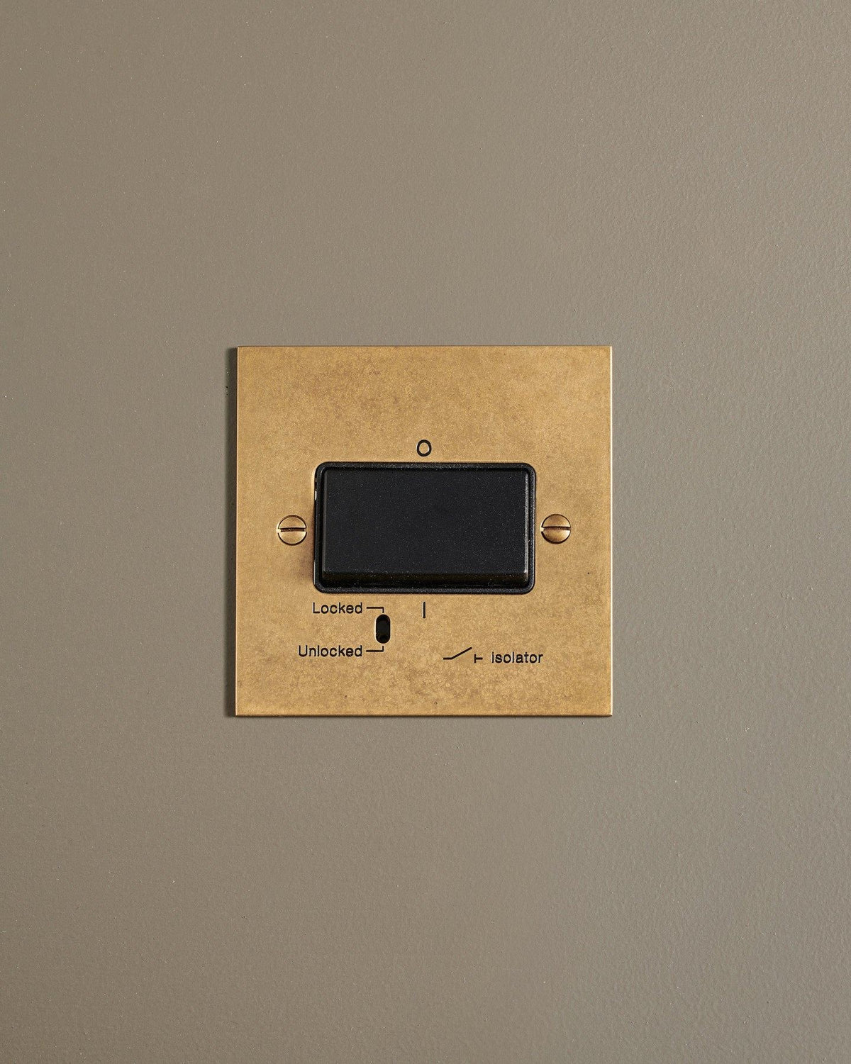 A straight-on view of a classic extractor fan isolator switch a mottled aged brass finish. TEST