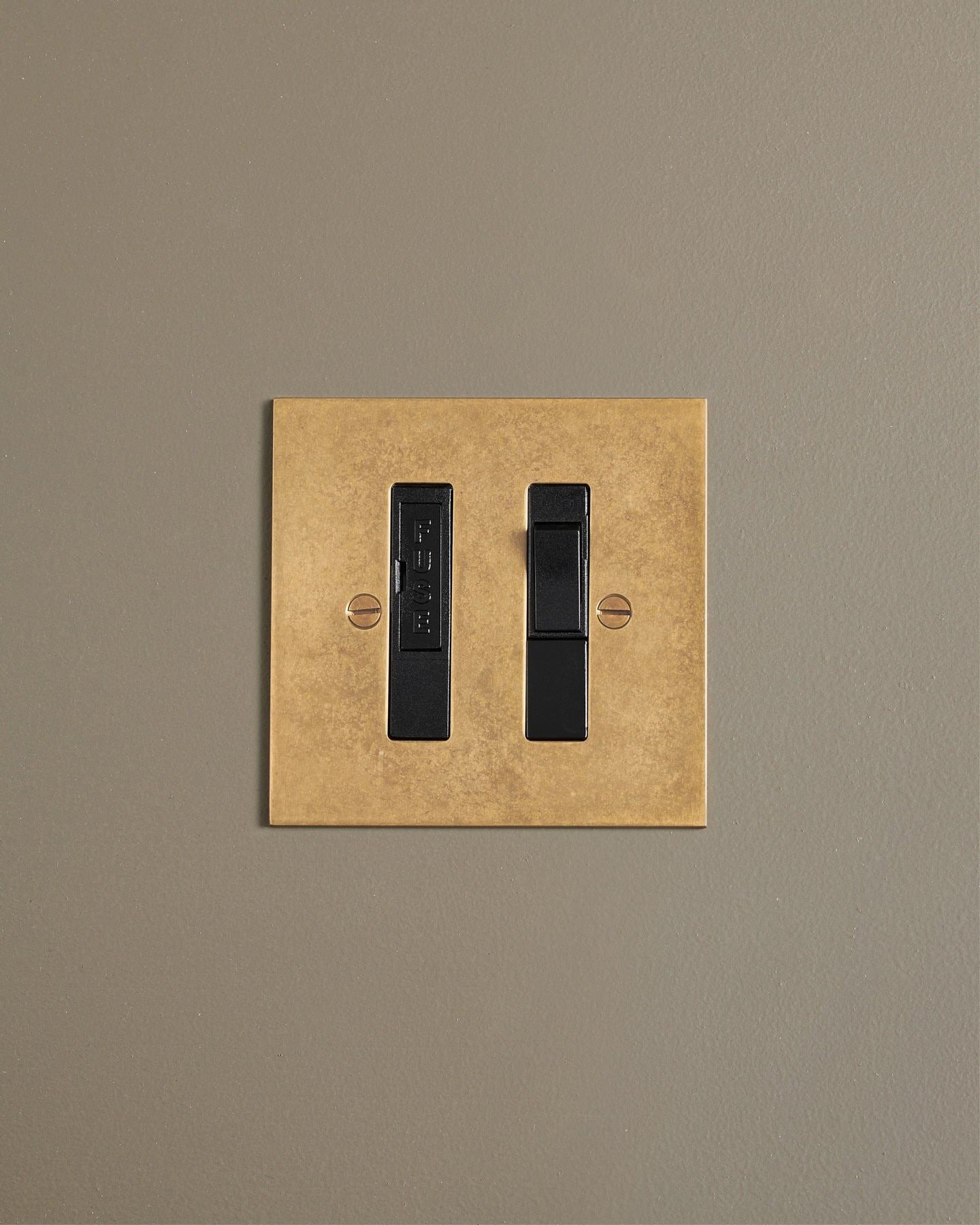 A straight-on view of a classic fused connection switch in a mottled aged brass finish.