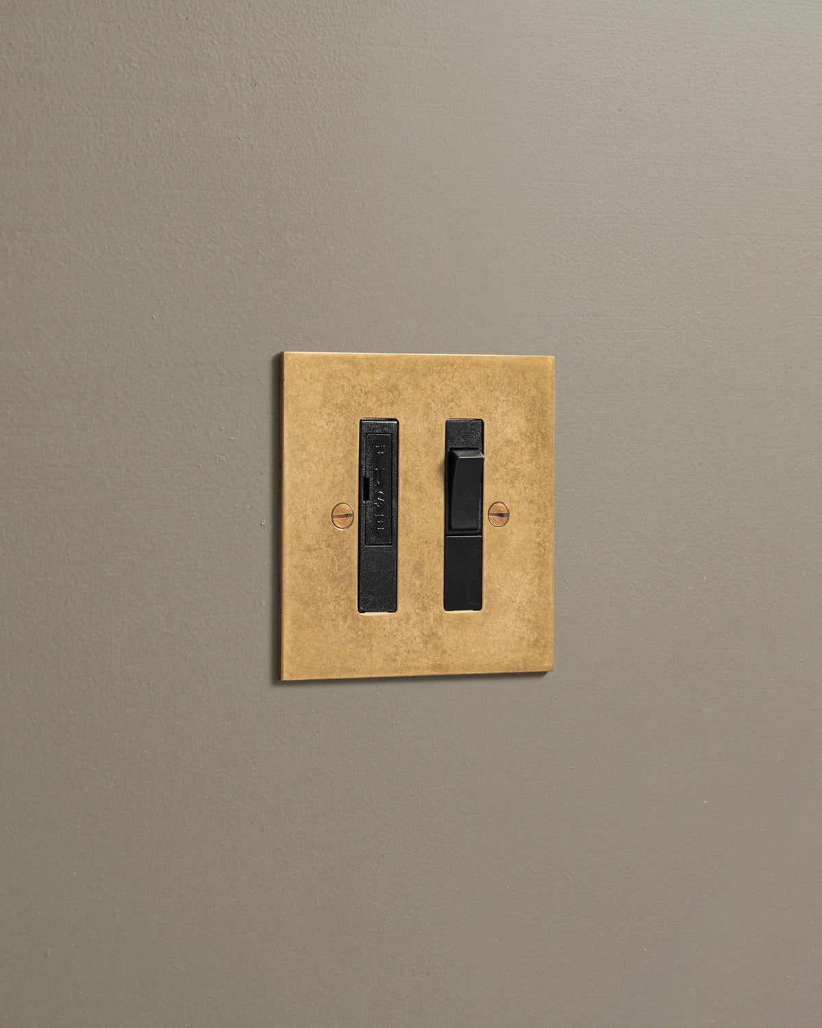 An oblique view of a classic fused connection switch in a mottled aged brass finish. TEST