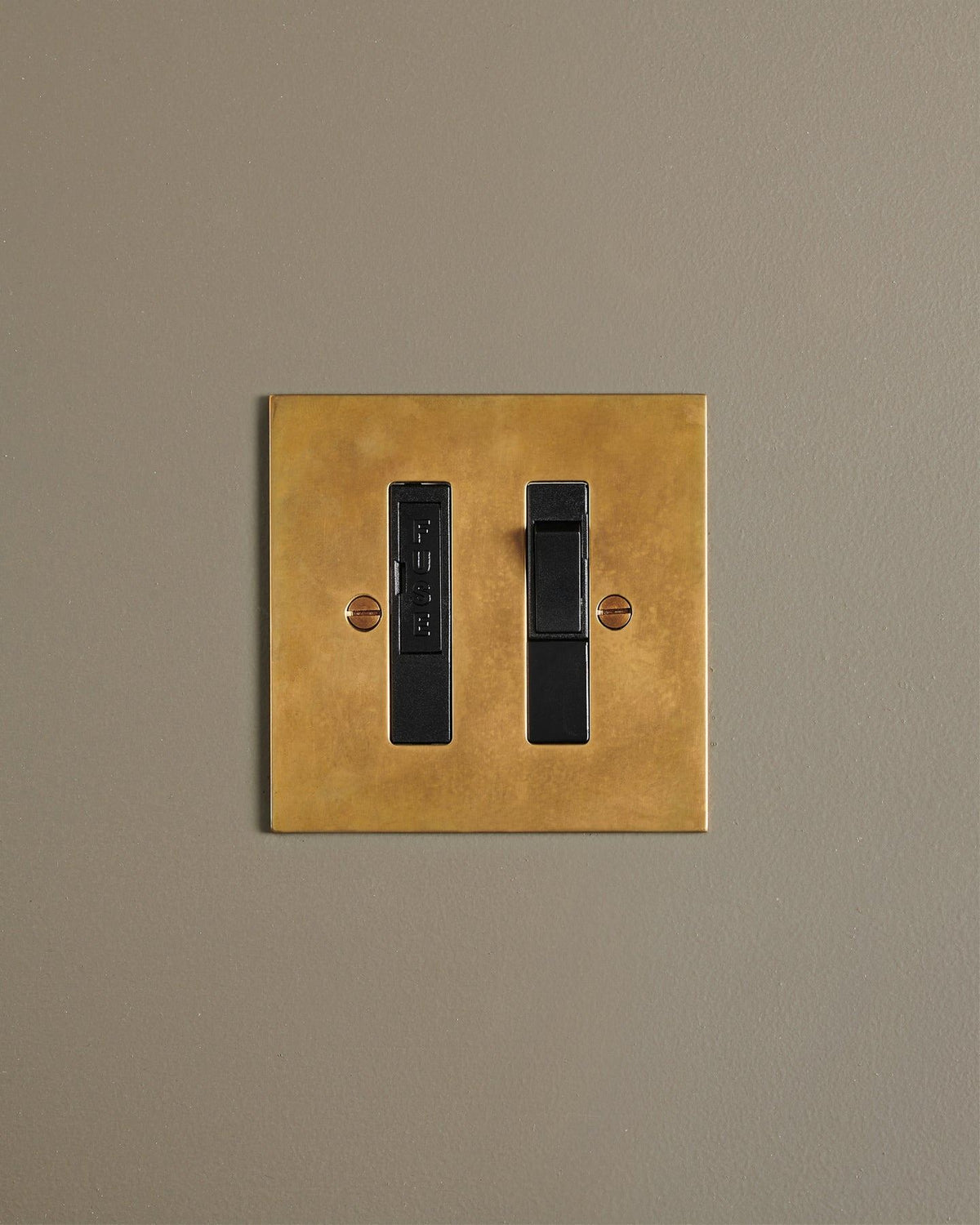 A straight-on view of a classic fused connection switch in a warm burnished brass finish. TEST