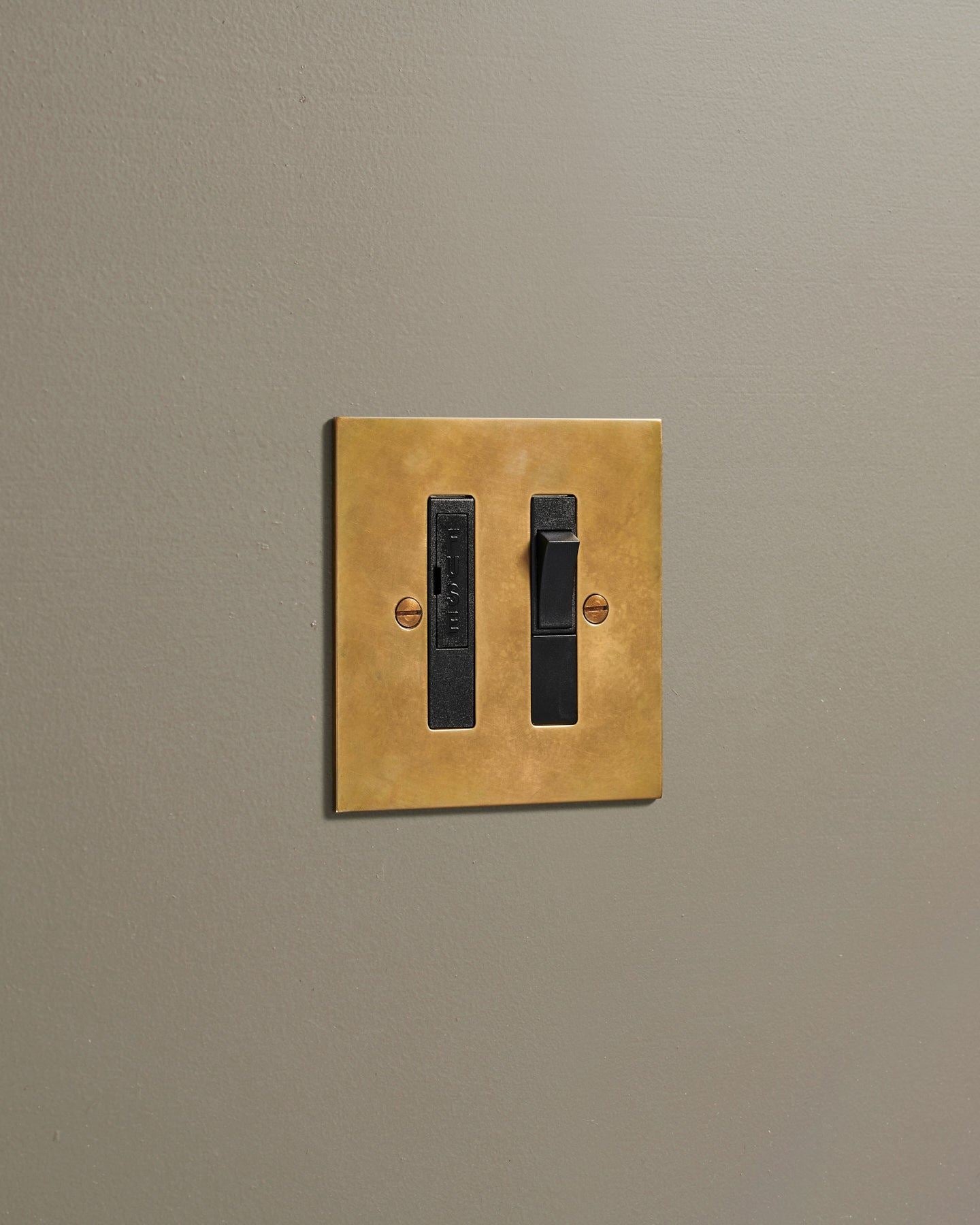 An oblique view of a classic fused connection switch in a warm burnished brass finish.