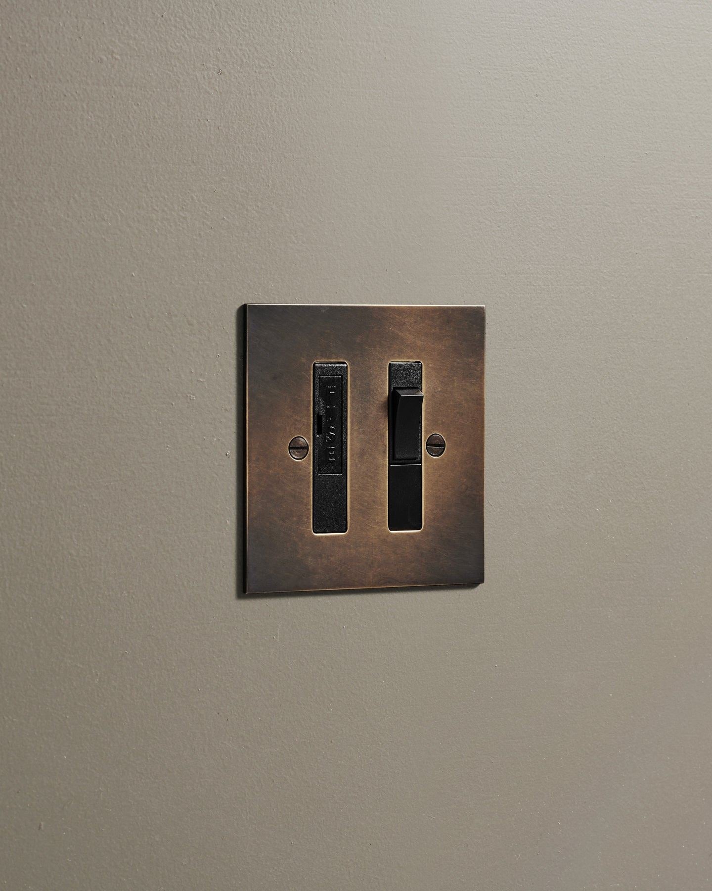 An oblique view of a classic fused connection switch in a dark oxidised brass finish.