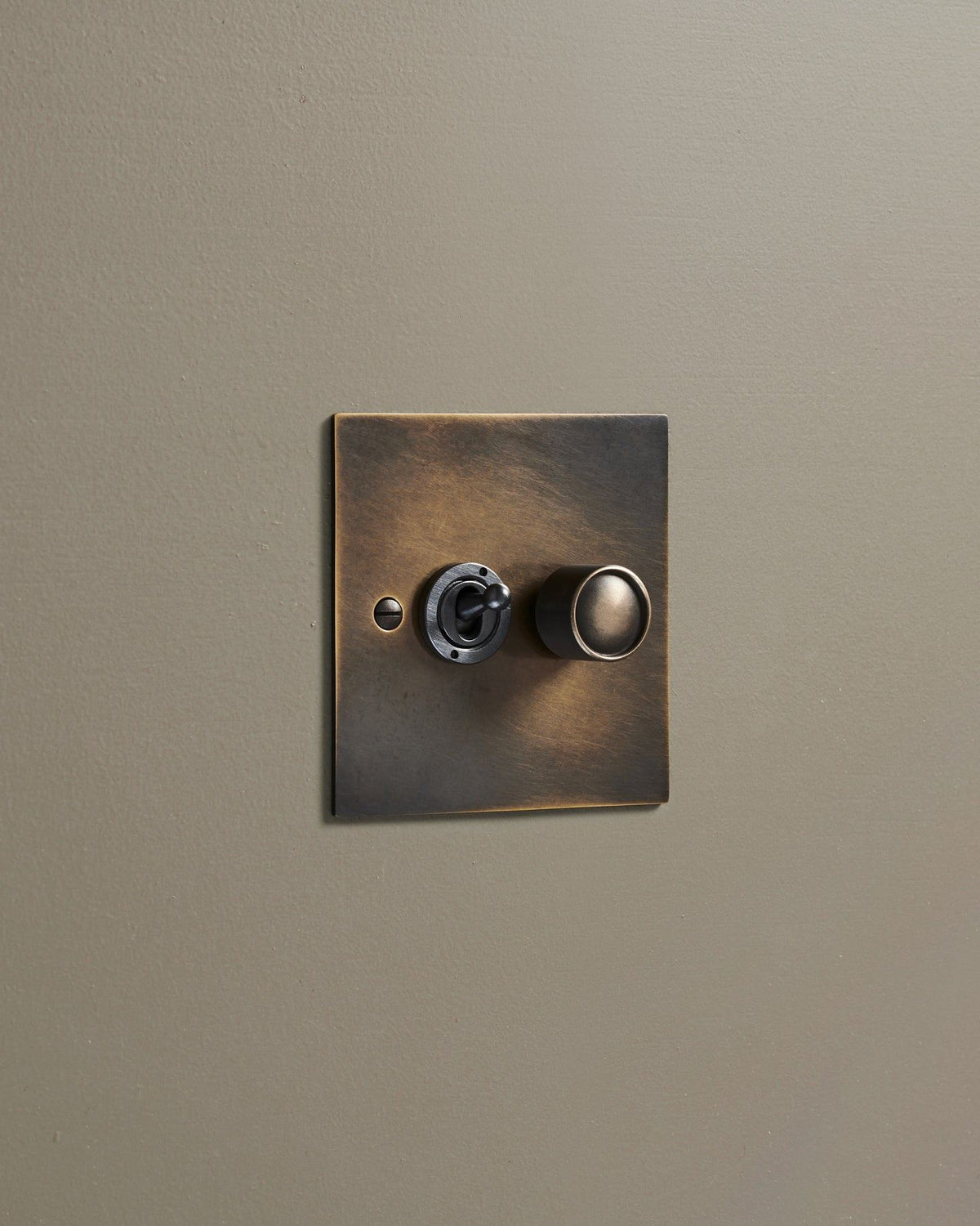 An oblique view of a 2 gang classic toggle and dimmer mixed switch in a dark oxidised brass finish. TEST