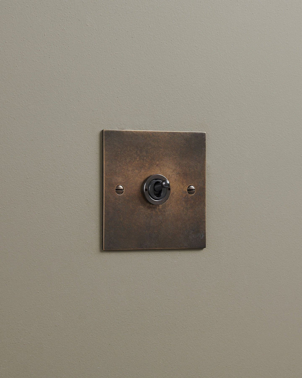 An oblique view of a 1 gang classic toggle switch in a dark oxidised brass finish. TEST