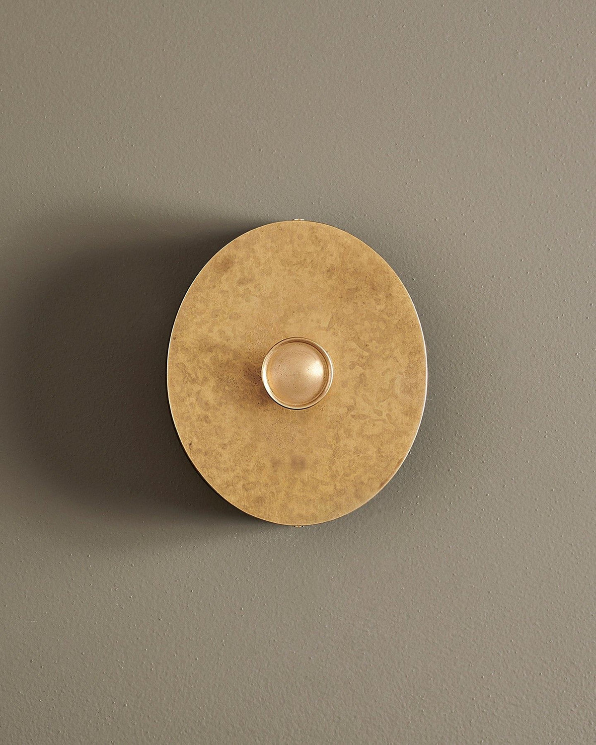 A straight-on view of a 1 gang oval-shaped dimmer switch in a mottled aged brass finish with a black base. TEST