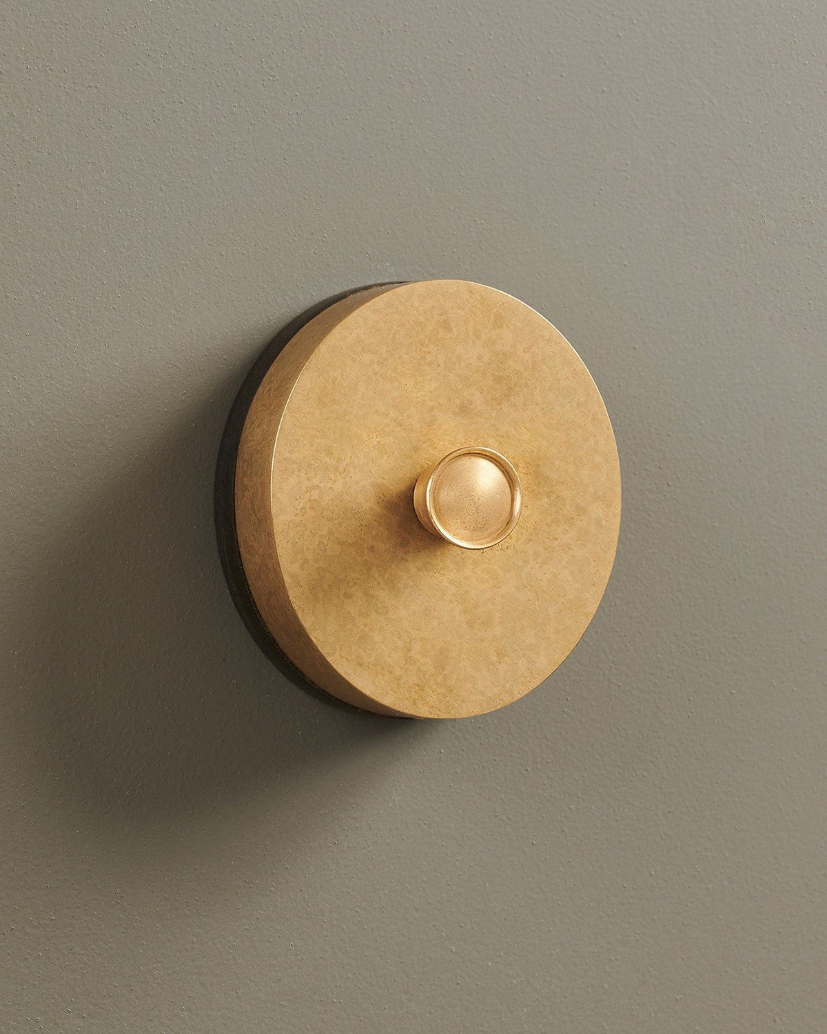 An oblique view of a 1 gang oval-shaped dimmer switch in a mottled aged brass finish with a black base. TEST
