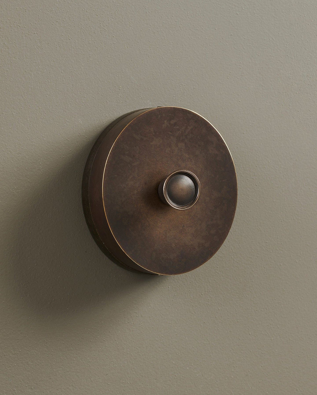 An oblique view of a 1 gang oval-shaped dimmer switch in a dark oxidised brass finish with a black base. TEST