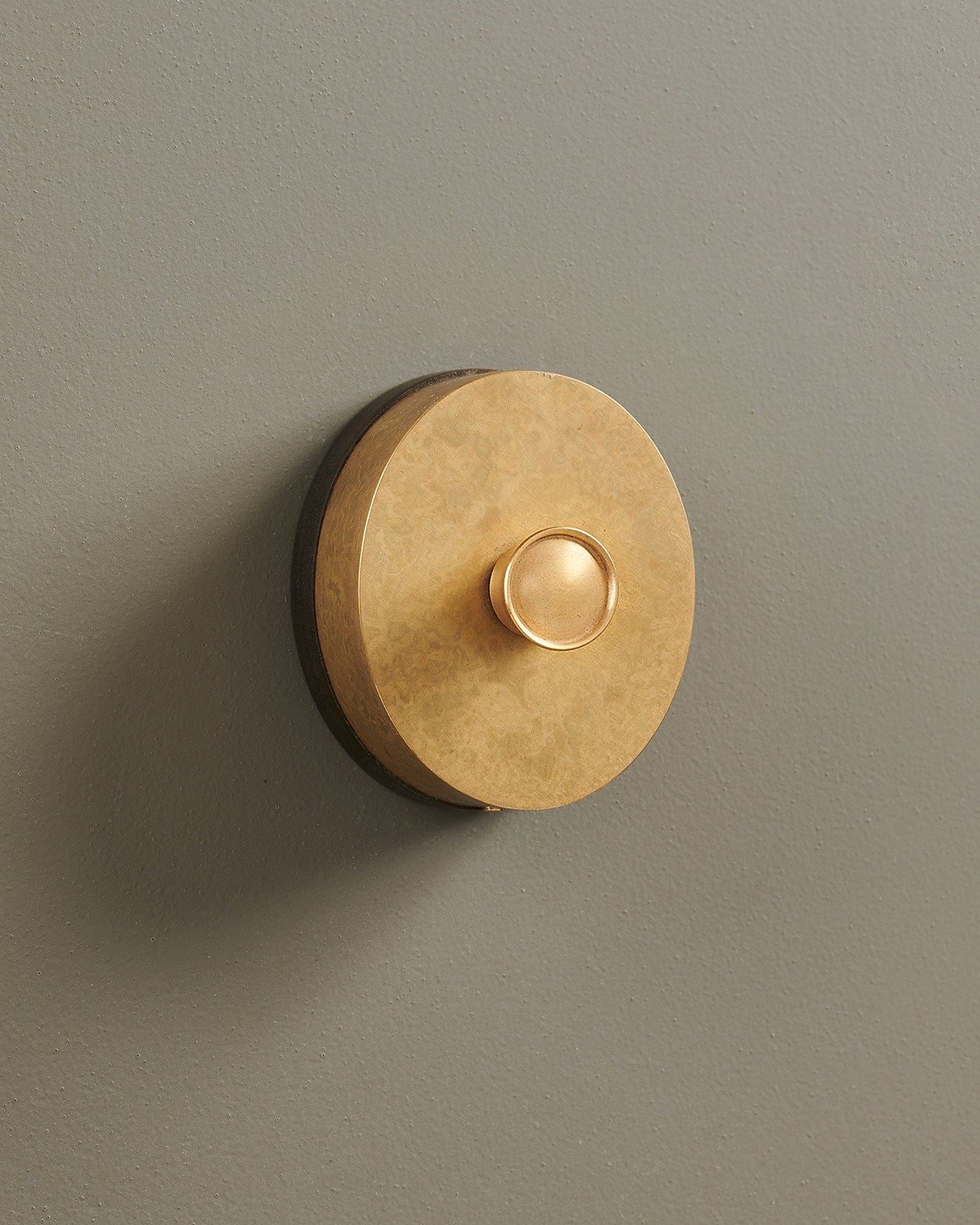 An oblique view of a small 1 gang oval-shaped dimmer switch in a mottled aged brass finish with a black base.