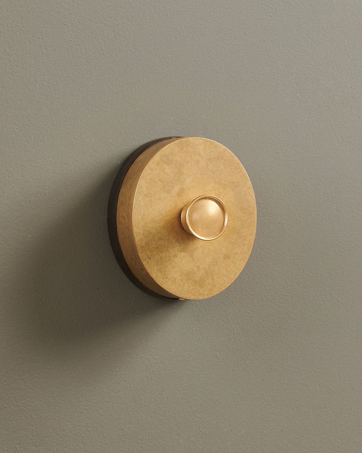 An oblique view of a small 1 gang oval-shaped dimmer switch in a mottled aged brass finish with a black base. TEST