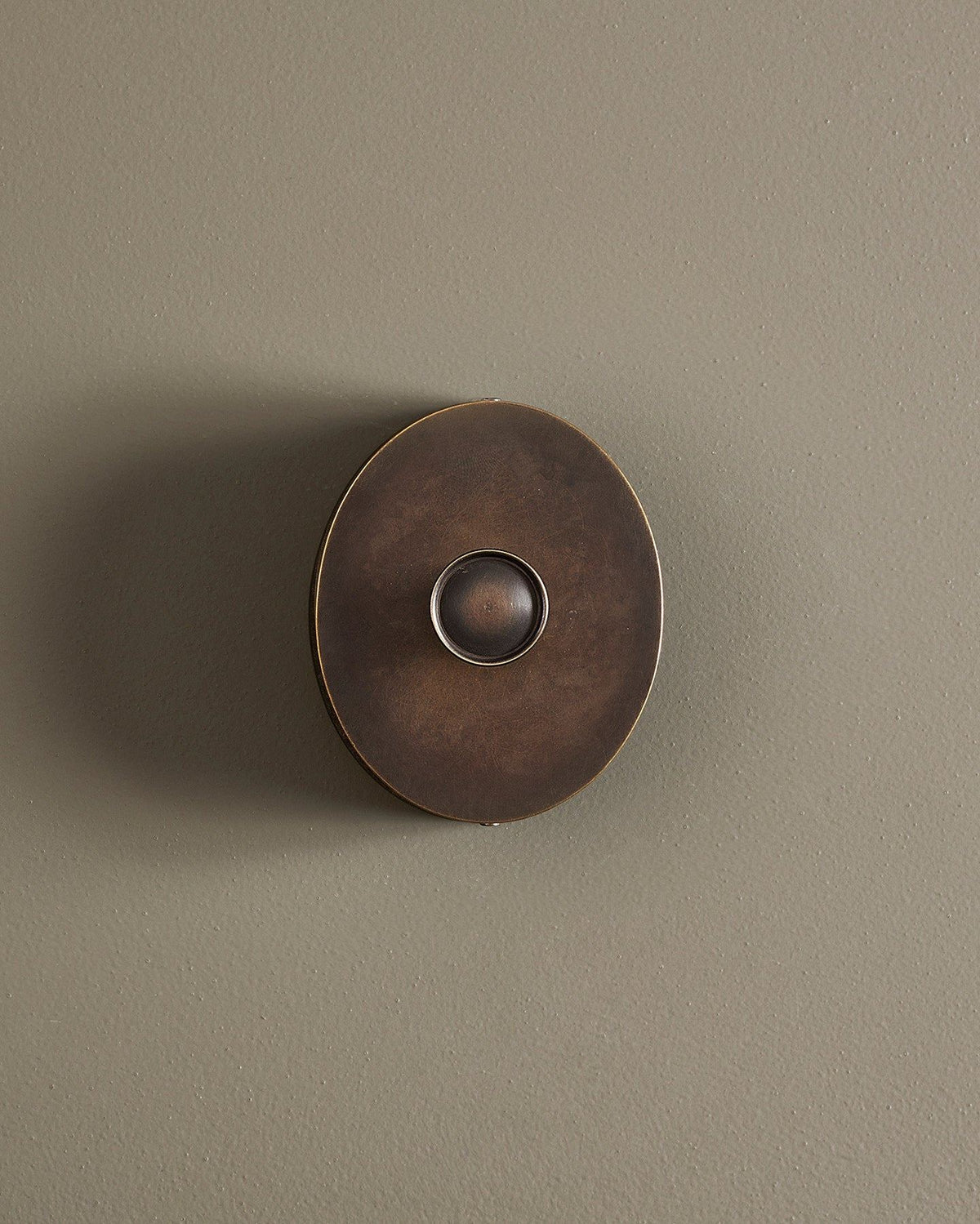 A straight-on view of a small 1 gang oval-shaped dimmer switch in a dark oxidised brass finish with a black base. TEST