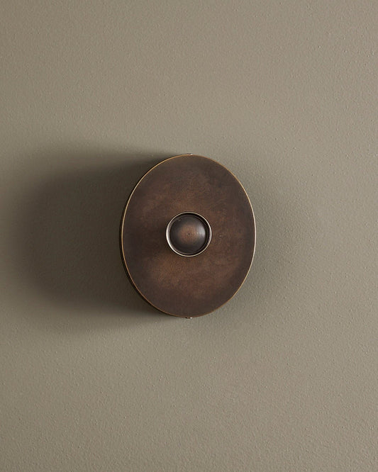 A straight-on view of a small 1 gang oval-shaped dimmer switch in a dark oxidised brass finish with a black base.