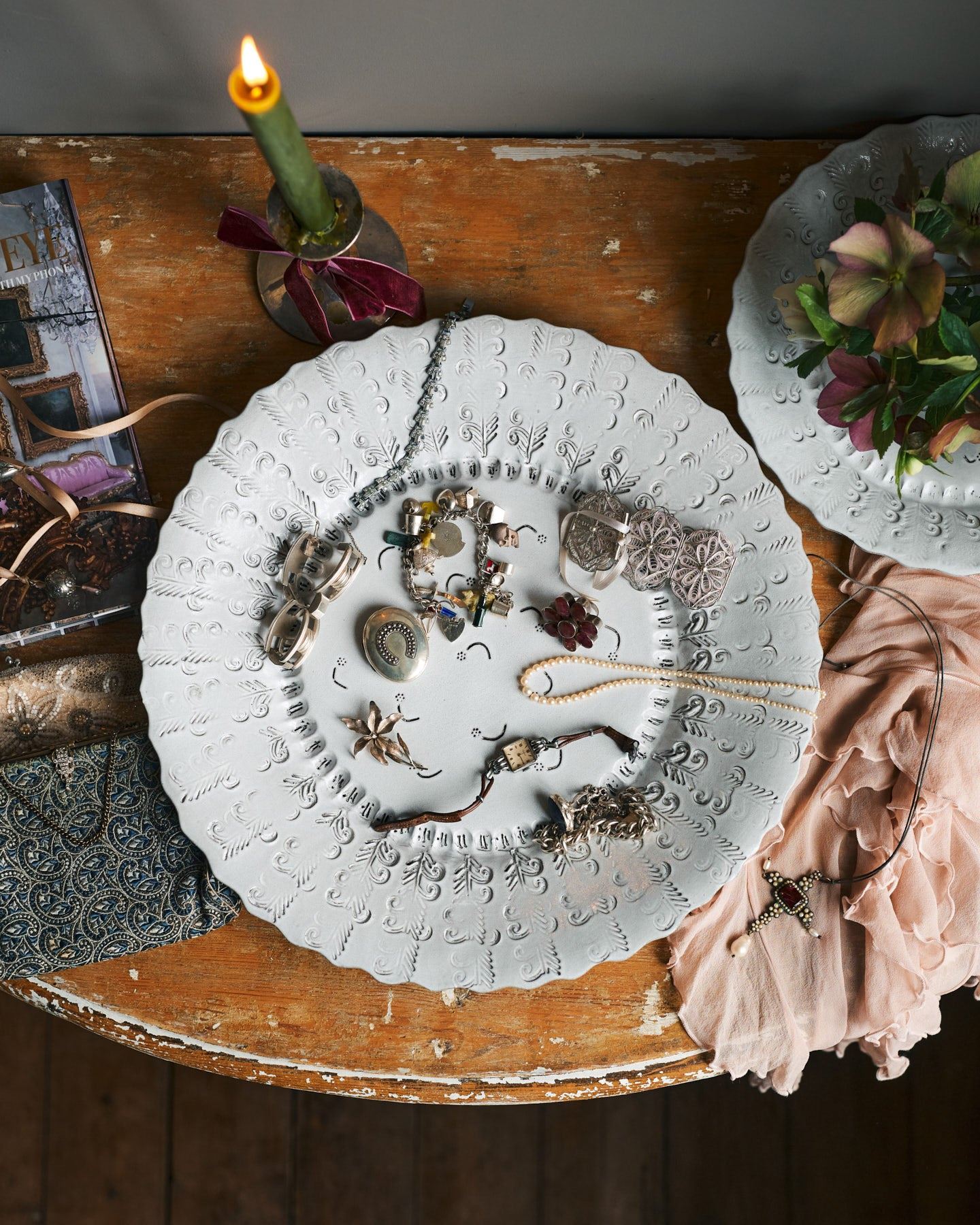 An overhead view of a large bohemian-style glossy white ceramic platter with a scalloped rim and delicate impressions and surface patterns.