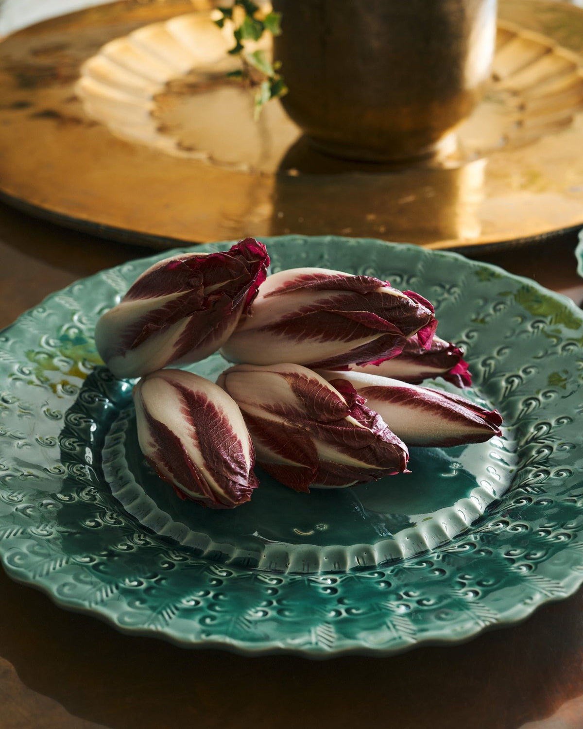 Red chicory on a large handmade bohemian-style green ceramic platter with a scalloped rim and delicate impressions and surface patterns. TEST