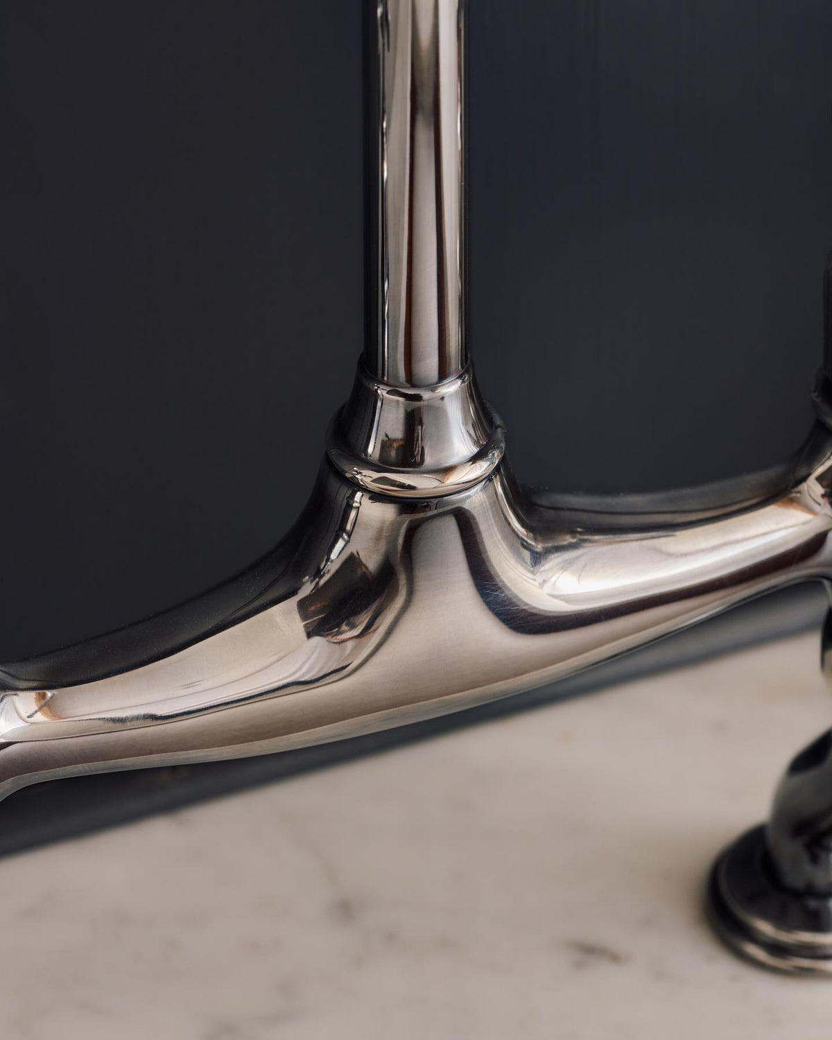 A close-up view of the body of a traditional-style tarnished silver mixer tap with crosshead handles. TEST