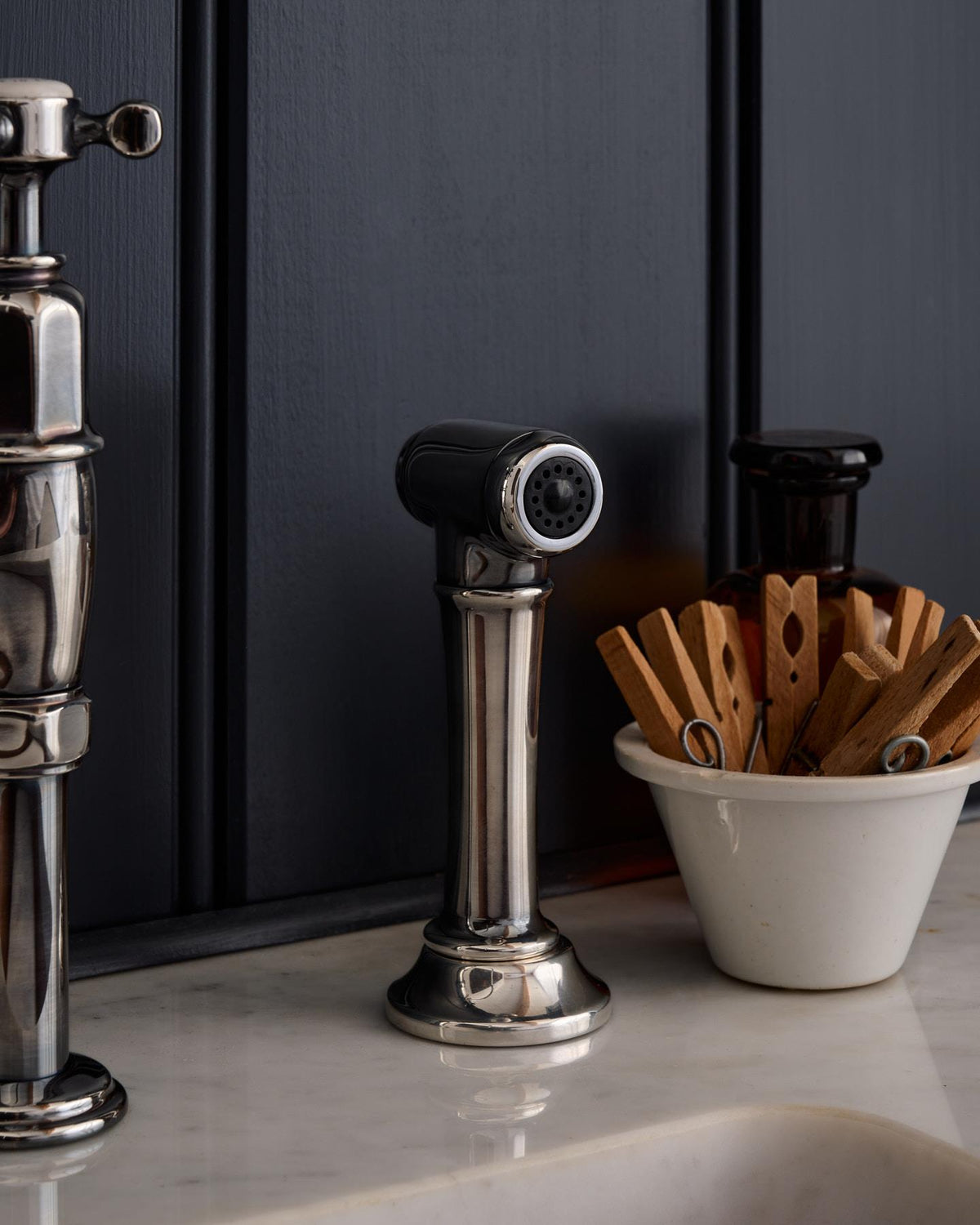 A close-up view of a traditional-style tarnished silver rinser tap. TEST
