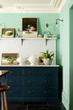 A quiet corner of a stunning, Bond Street blue kitchen features a cooker run with Arabescato marble worktop and splashback. The room features a stunning mix of colours and character, accentuated by elegant antiques such as a collection of porcelain figures, artisan ceramics, and still paintings.