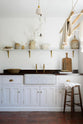 The simple and functional linen white scullery room with a modest sink run with polished sapele, a large single Carrara marble sink, and aged brass Mayan taps. The warm reds and browns of the terracotta square tiles, vintage furniture, ceramics, woven baskets and a deVOL laundry maid serve the room with both a purpose and beautiful aesthetics.