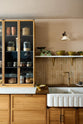 A quiet corner of a warm and chic Haberdasher’s kitchen featuring an L-shaped sink and cooker run, countertop cupboards, a Carrara and copper mix worktop, and a double-fluted marble sink. Adorned with artisan ceramics, Heirloom wall lights, dried ingredients in glass jars, and a vintage green scale, this kitchen creates a warm and inviting Spanish-inspired space in Yorkshire.