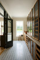 A smart and functional Haberdasher’s pantry features a long pantry run with glazed, open cupboards that include internal drawers and tambour doors, along with a Carrara marble worktop and shelves. Beautifully decorated with eye-catching diamond mosaic flooring, vintage items, books, and loaves of bread, this pantry creates a warm and neat storage space.