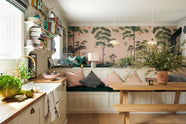 A vibrant Shaker kitchen features an L-shaped sink and cooker run with a solid oak worktop, a single Belfast sink, an aged brass Ionian tap, a Shaker shelf, and a bench. Lovingly decorated with pink rainforest wallpaper, colourful cushions, overstocked books, a record player, chattered skullcap porcelain lights, and a park bench dining table, it creates a characterful and inviting space.