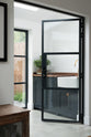 Past the black-framed French doors is a small sink run with a single sink, an aged brass Ionian tap, and a solid oak worktop. Adorned with a luscious green house plant, it creates a warm and social space.