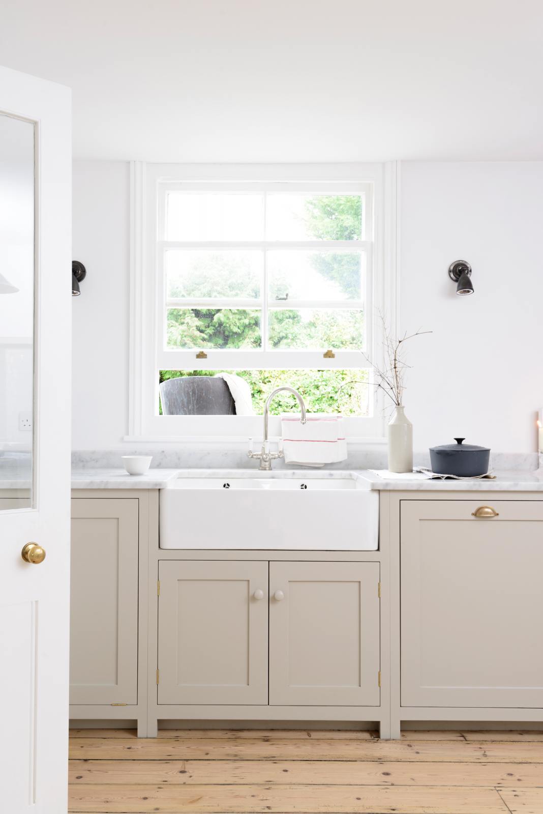 A simple mushroom-coloured shaker kitchen features a marble worktop, a double Belfast sink with an antique silver Ionian tap.