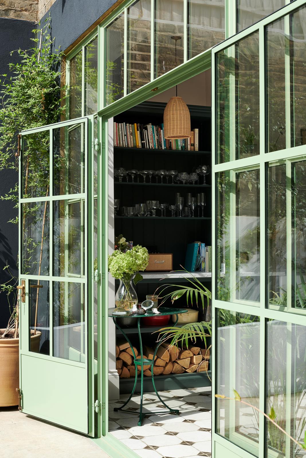 An angled view of the wide Crittall windows painted pistachio green, alongside the Bakehouse Green shaker kitchen with the reclaimed octagonal marble-tiled floor awaiting inside.