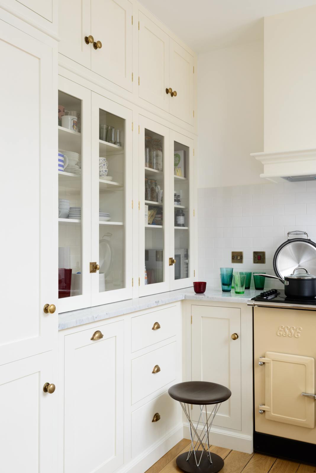 A closer look at the small but functional white linen kitchen featuring a shaker canopy, glazed cupboards, drawers, and a white porcelain splashback.