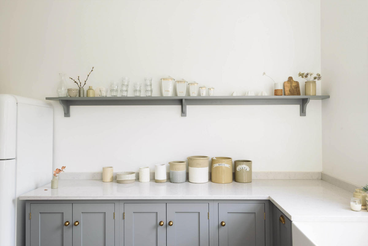 A light and bright Shaker kitchen features an L-shaped sink run with a double sink, an aged brass Ionian tap, Silestone worktop, and a Danmask prep table with a solid oak worktop. Beautifully decorated with soft artsian ceramics, and antique collectables, it creates a wonderfully warm and contemporary space.