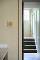 A close-up shot of a deVOL’s petite oval dimmer switch in a traditional and warm heirloom brass finish, fitted in a simple basement kitchen of a Georgian townhouse. There is a beautiful contrast between the glow of the brass dimmer switch and the earthy tones of the greeny-beige painted walls.