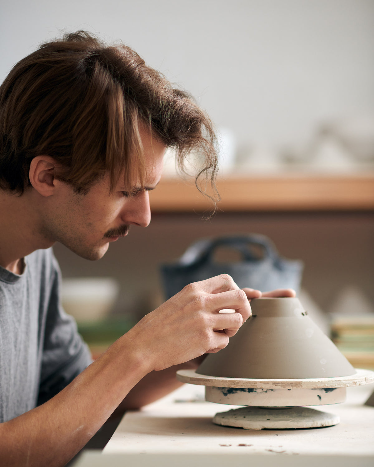 A ceramicist carefully poking air holes in the clay porcelain lamp piece.