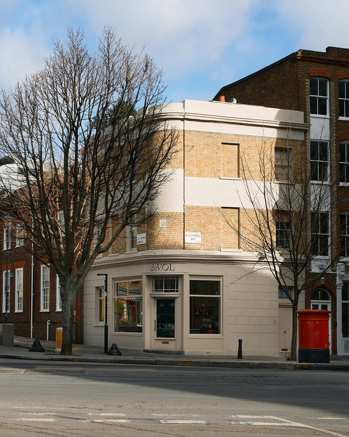 The deVOL St Johns Showroom in London is a corner, three floor, cream bricked building with strips of light beige painted exterior and a hand painted logo on top of the front door.