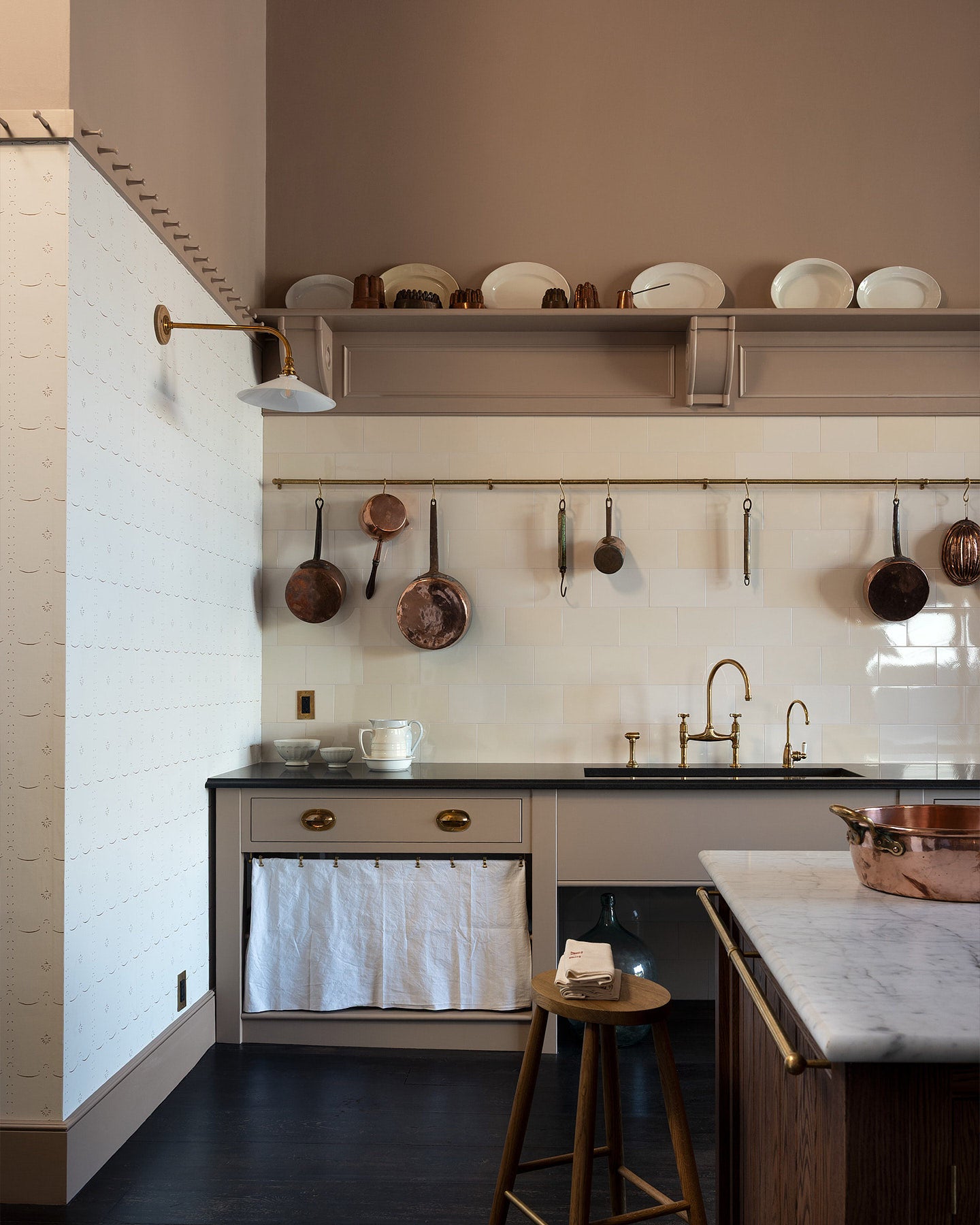 A grand and spacious Heirloom kitchen with a Princelet pink sink cabinet and Butler Pantry, and an Heirloom Dairy Table. Beautifully decorated with a Cream Subway splash back tiles wall, a long aged brass hanging rail, copper pots and pans, and vintage artisan ceramics.