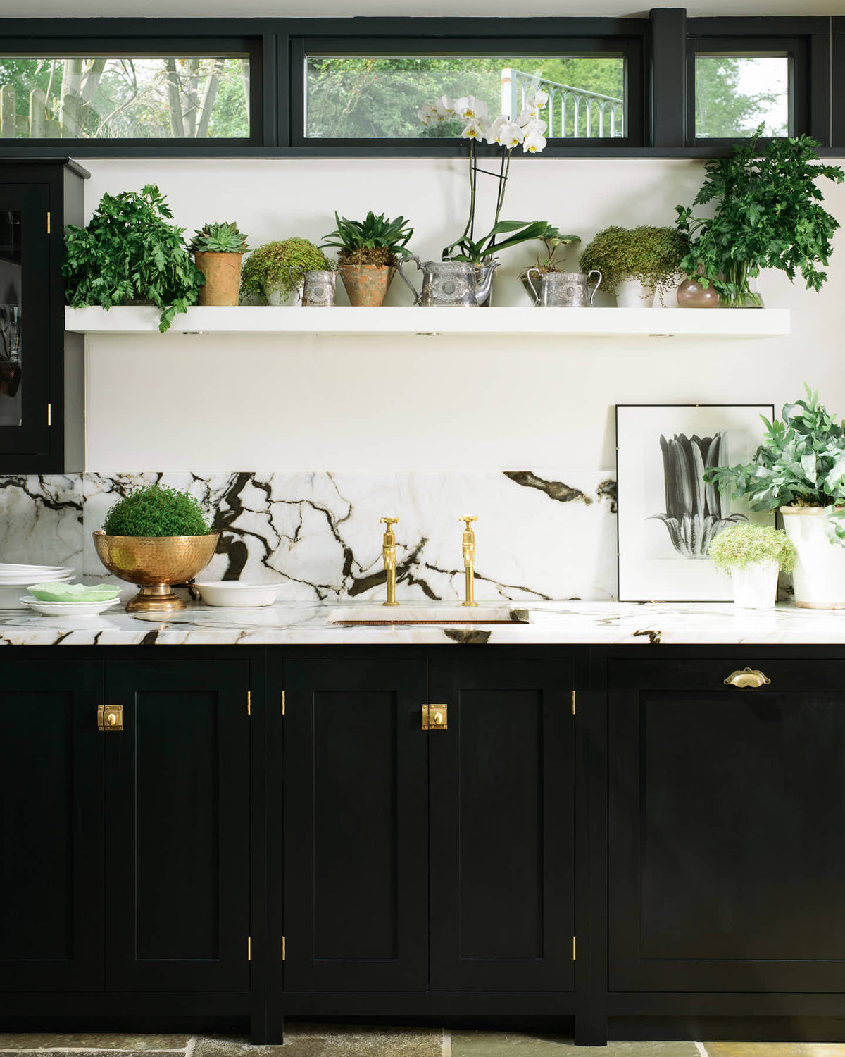 This beautifully renovated kitchen features a Painter’s Black shaker style with an L-shaped layout that includes a cooker and sink run. The worktop and splash back are made from San Simone quartzite, complemented by an overhead glazed cupboard and a tall storage cupboard. A glass skylight brightens the modern space while honouring the historical character of the building by retaining the original brick wall.