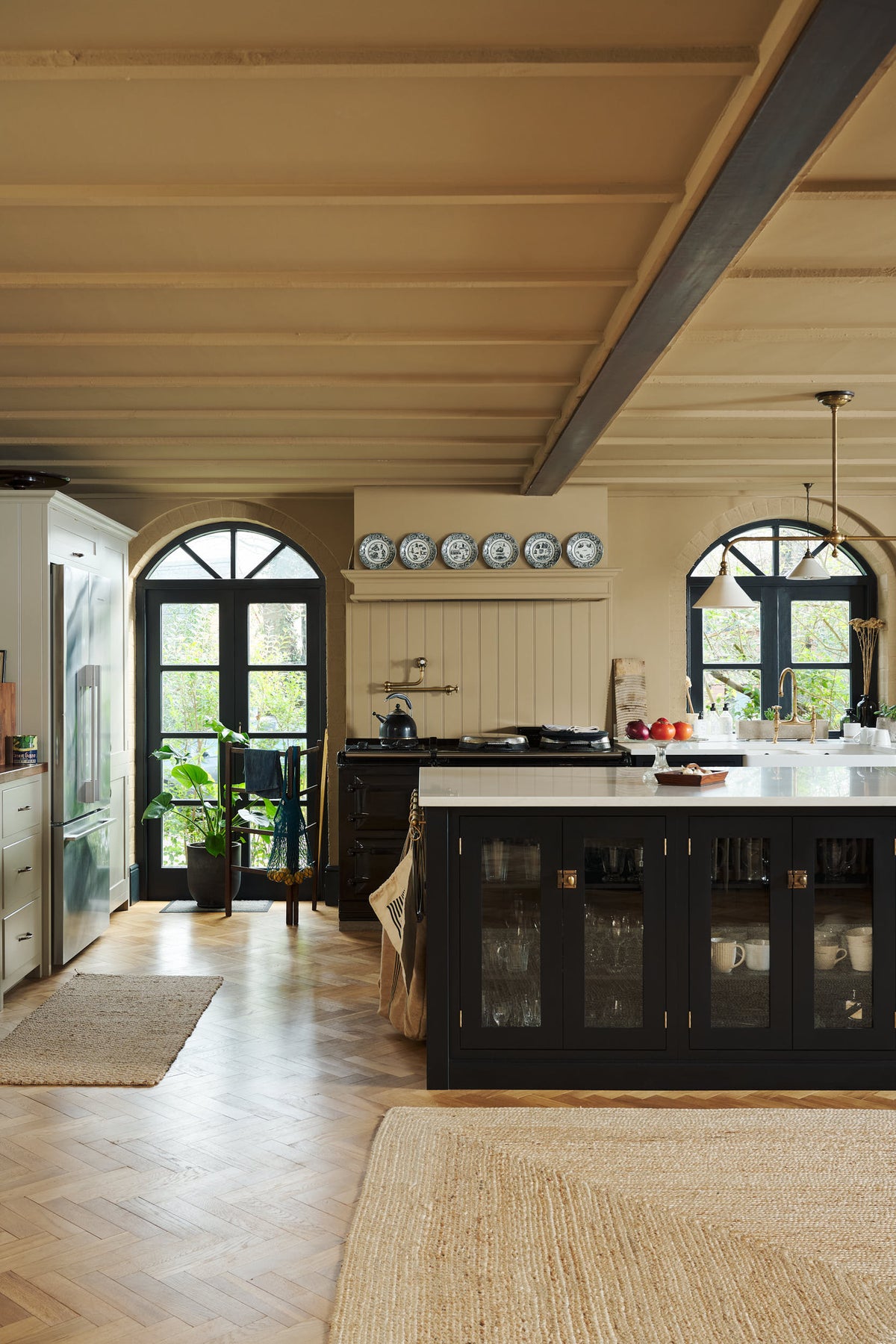 Past through the glass partitions, is a wide open social space that includes a Painter's black Shaker kitchen and Mushroom pantry. Busy with a lot of kitchen utilities, plants, and beloved furniture and ceramics, the space is an incredibly inviting and comfortable family room.