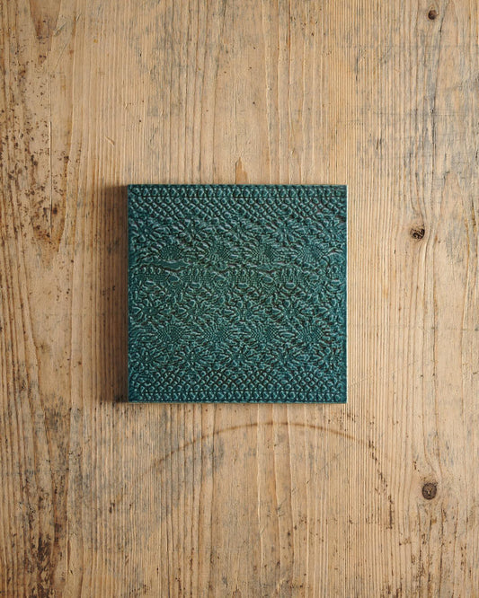 Teal textured square on a wooden surface. | Venetian Square