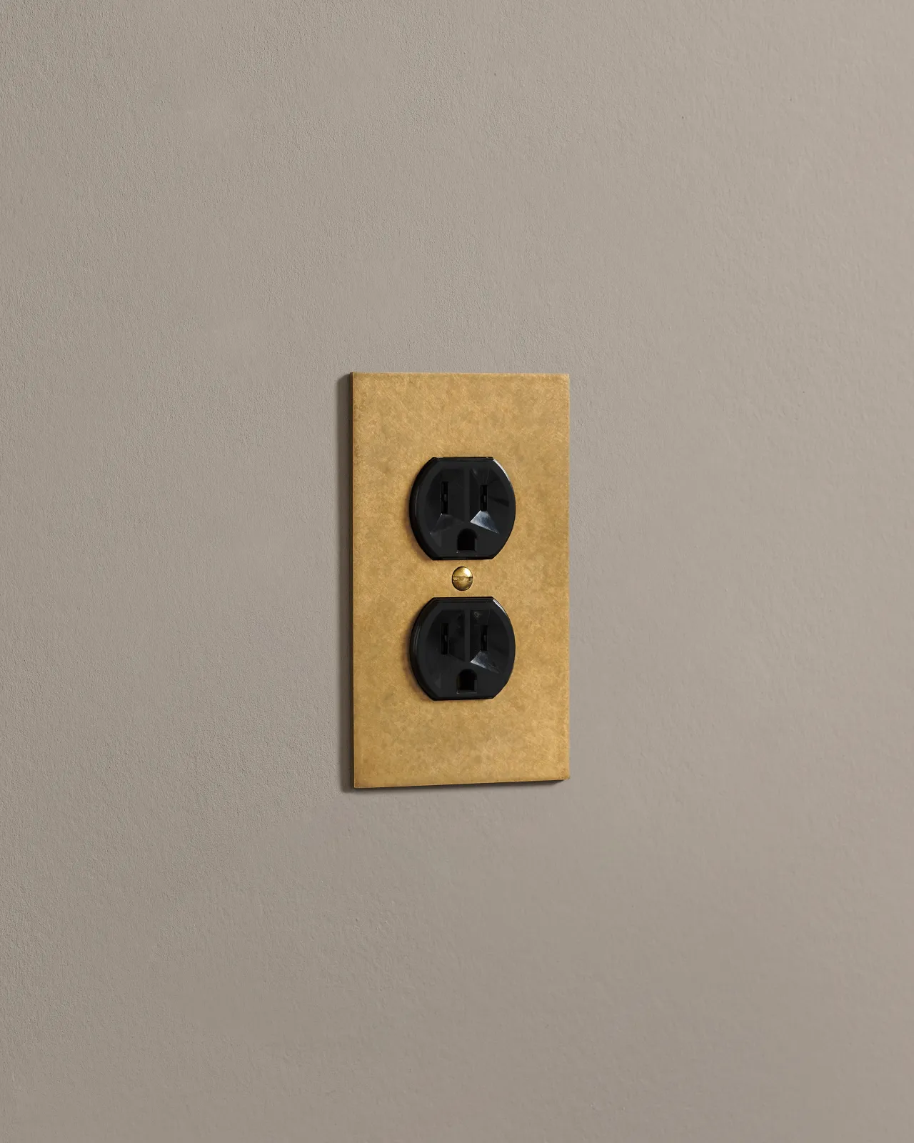 A side on shot on a duplex outlet on an aged brass cover plate.