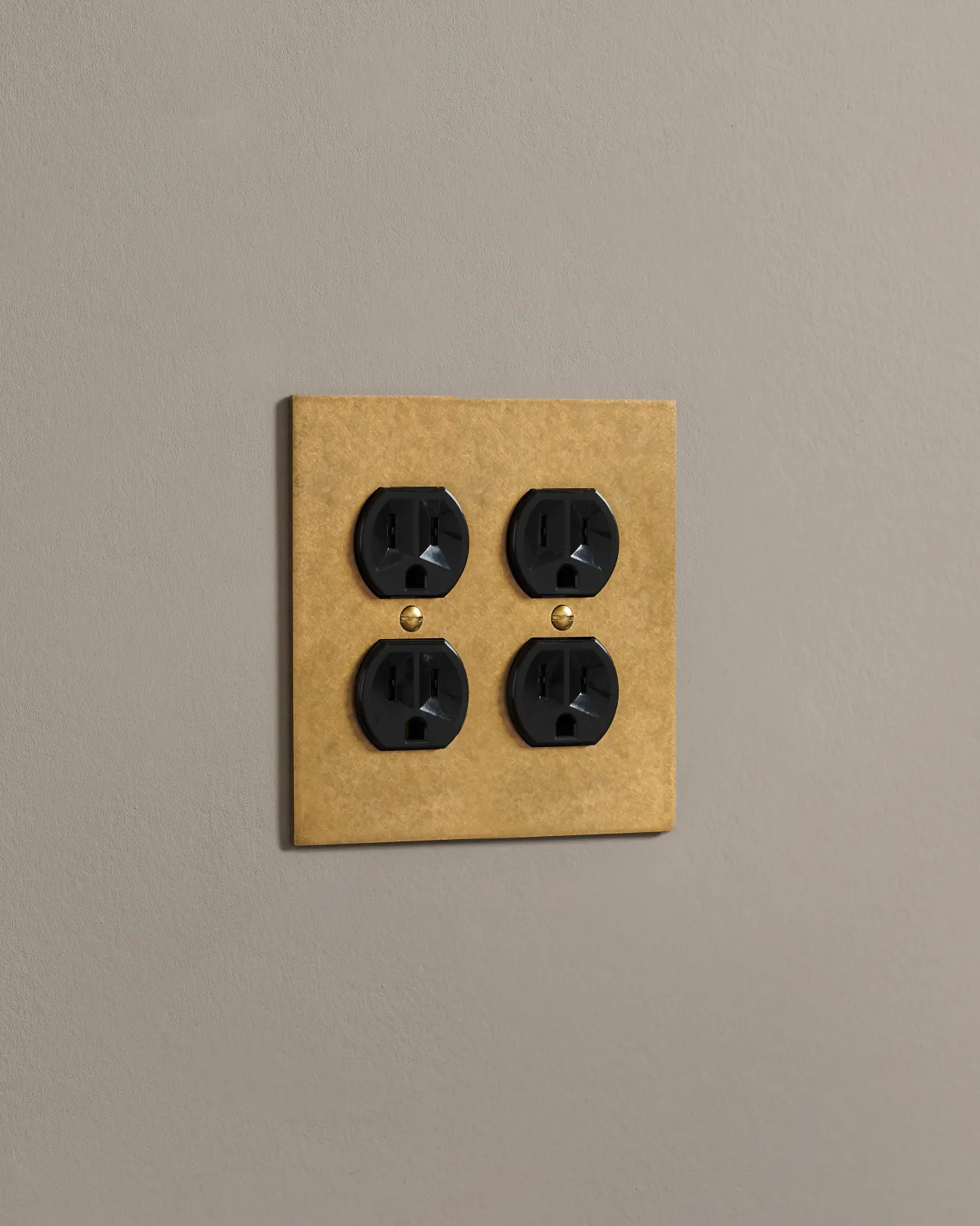 A side on shot on a duplex outlet on an aged brass cover plate.