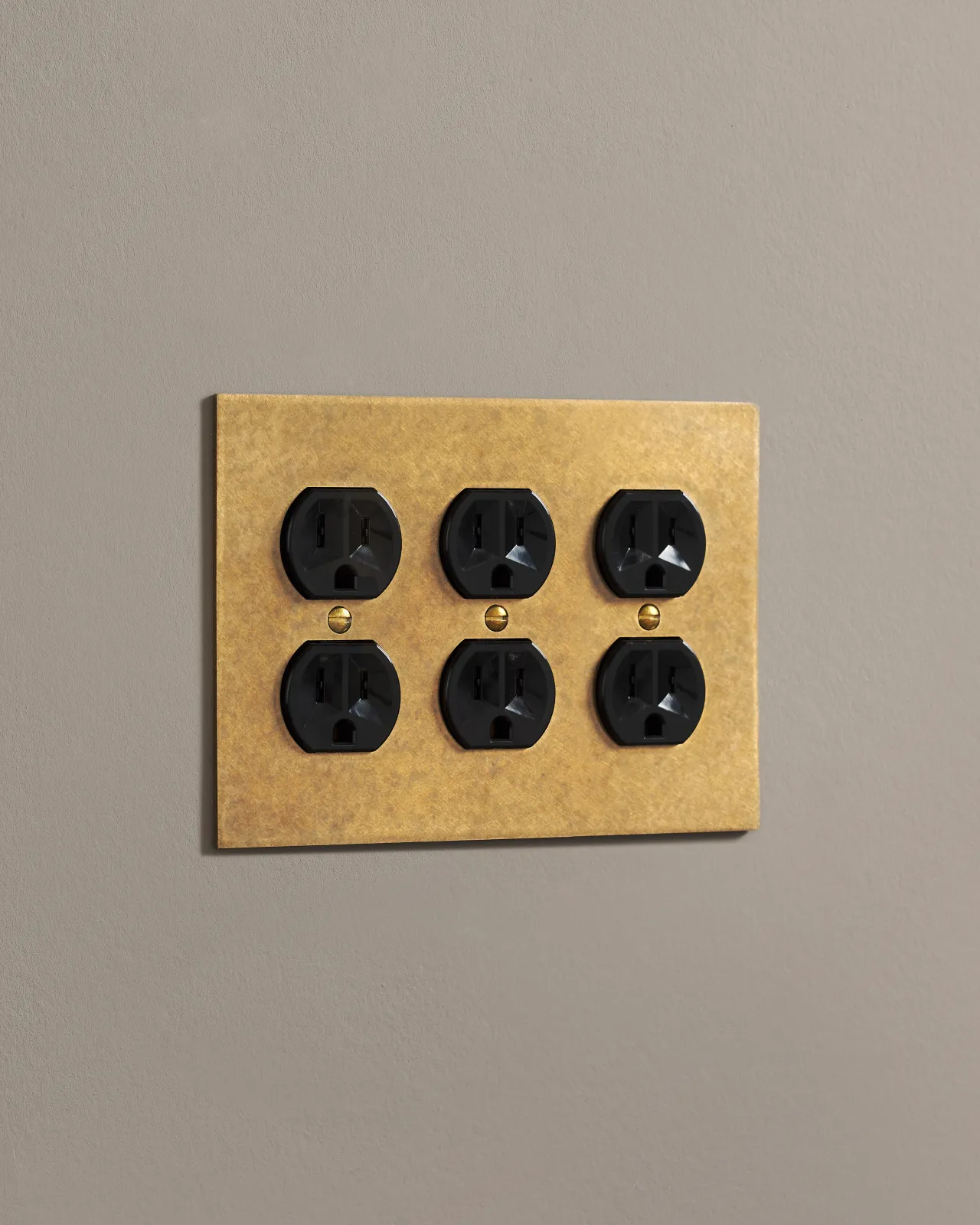 A side on shot on a duplex outlet on an aged brass cover plate.