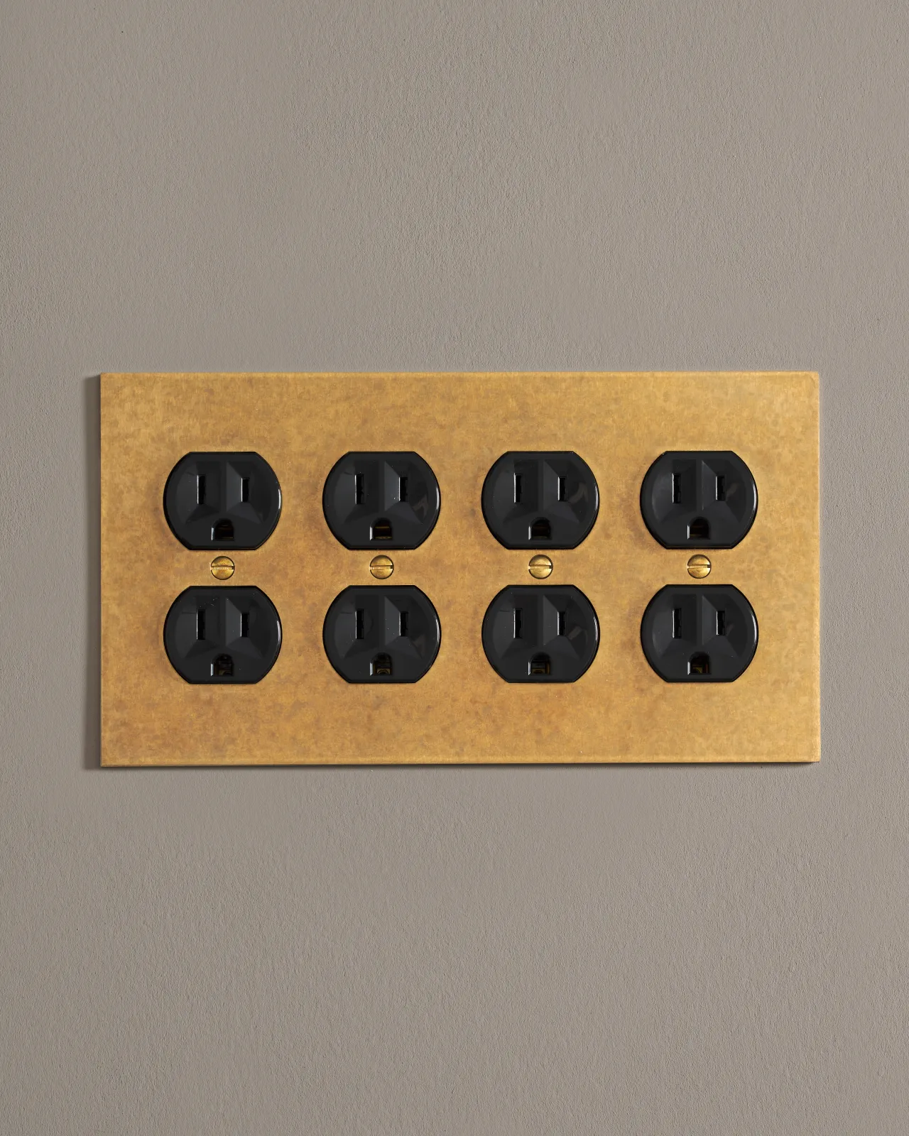 A front on shot on a duplex outlet on an aged brass cover plate.