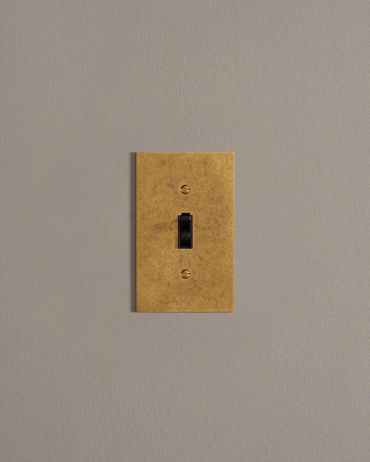 A front on shot on a toggle switch on an aged brass cover plate.